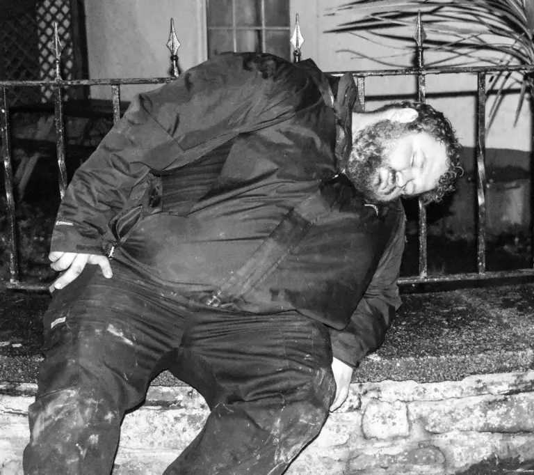 Black and white photo of a tar barrel runner bending down in the early hours