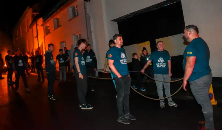 Team members lined up with ropes in the street before the tar barrels run
