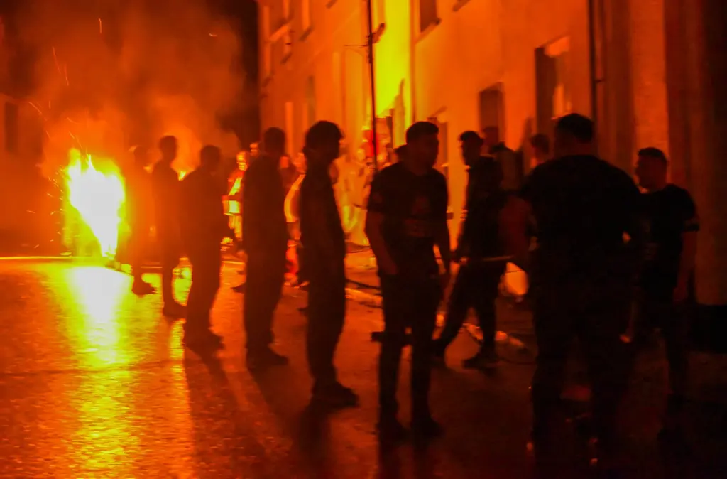 Silhouetted team pulling flaming tar barrels along the glowing street