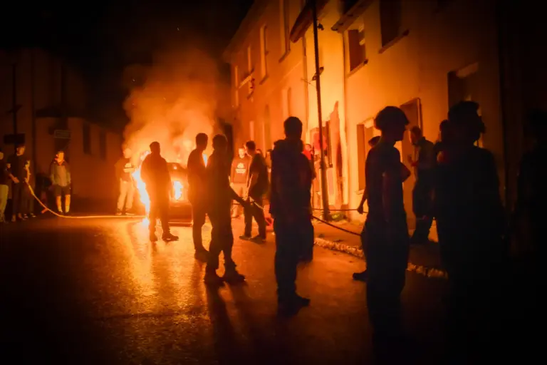 Team members hauling the blazing tar barrels through the town at night
