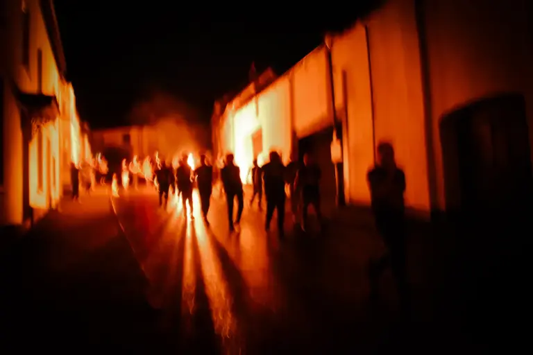 Long shadows cast by the flaming tar barrels along the town's walls
