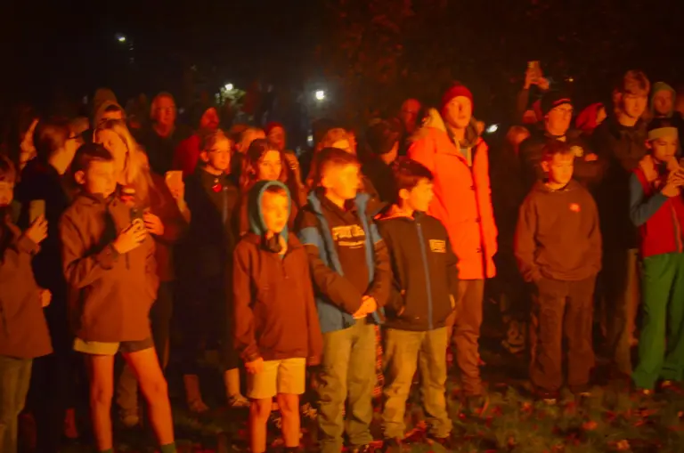 Crowd of children and families watching the bonfire, lit orange by the flames