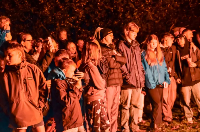 Young people watching the bonfire with faces glowing in the firelight