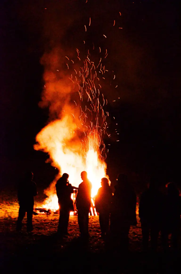 Figures silhouetted against a bonfire throwing a shower of sparks into the night