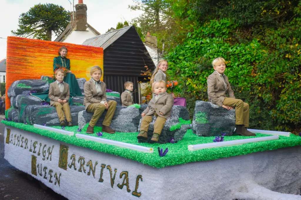 The Hatherleigh Carnival Queen float, decorated with a sunset backdrop and rocks, with the Queen and her young attendants