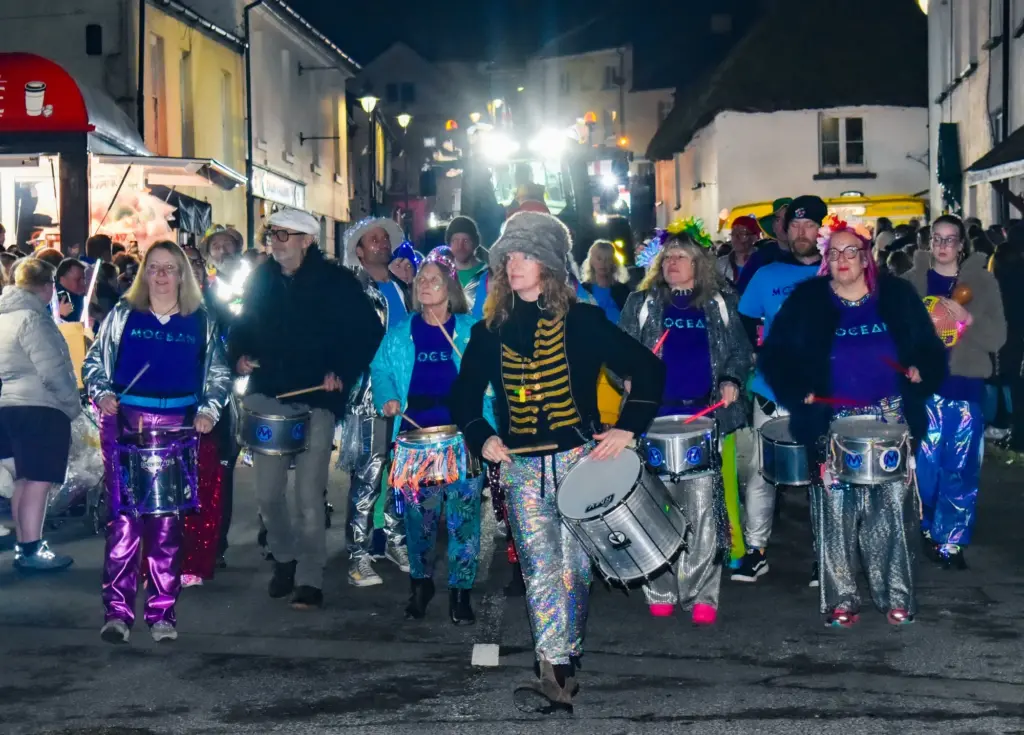 Samba drummers in sparkly costumes leading the night-time procession through Hatherleigh